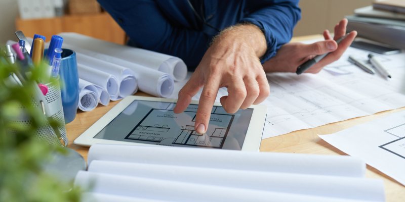 Close-up image of architect examining housing project on screen of tablet computer